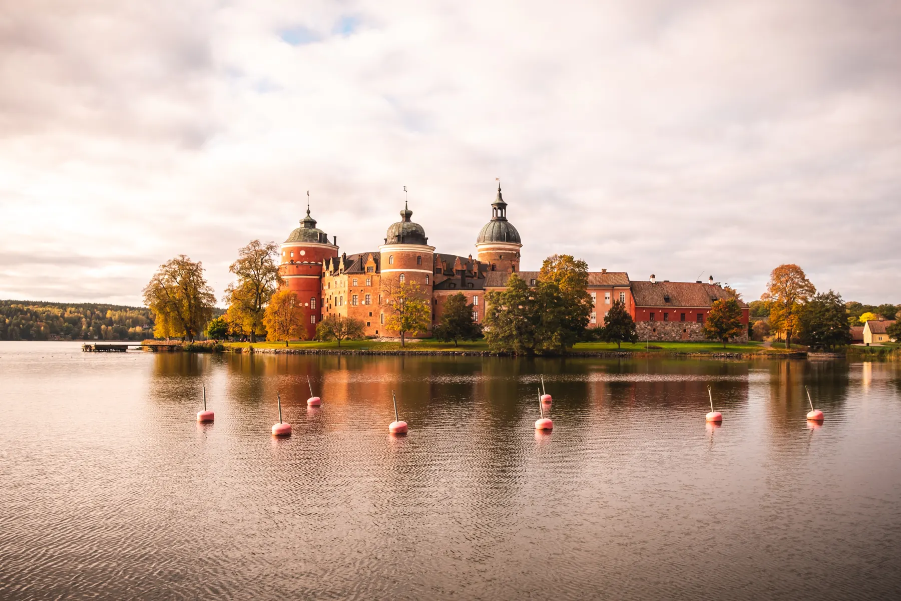 Gripsholms slott i varmt ljus med vatten och speglingar i förgrunden