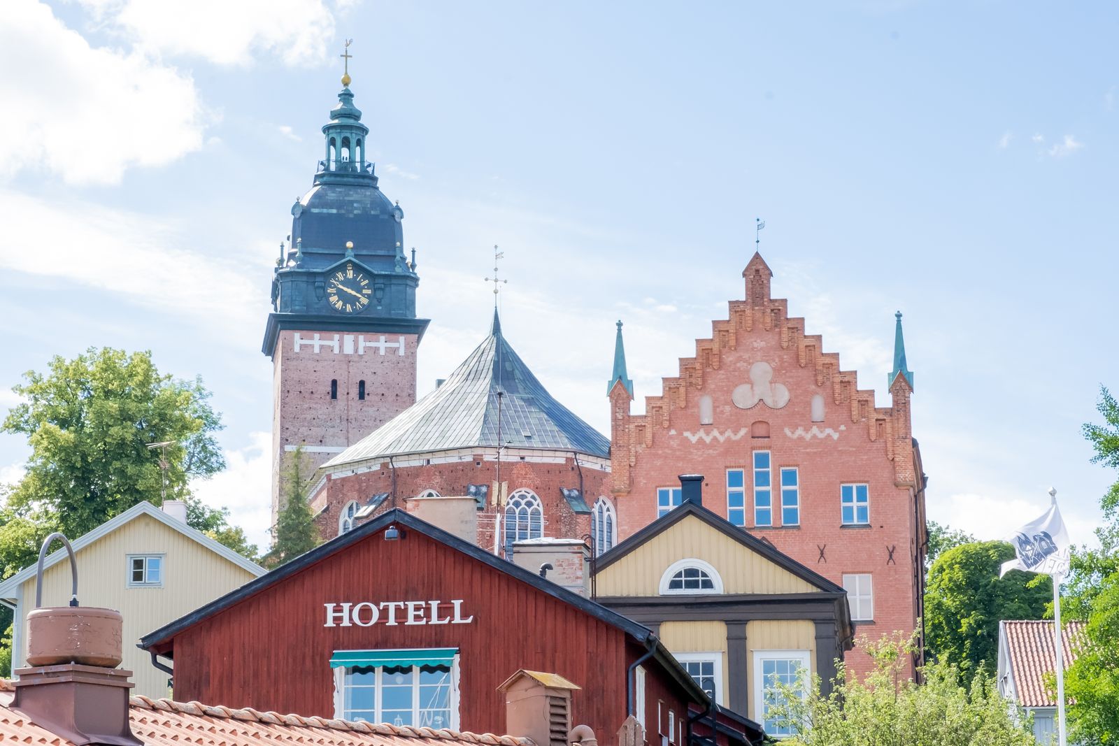 Strängnäs domkyrkas torn bakom röda tegelbyggnader
